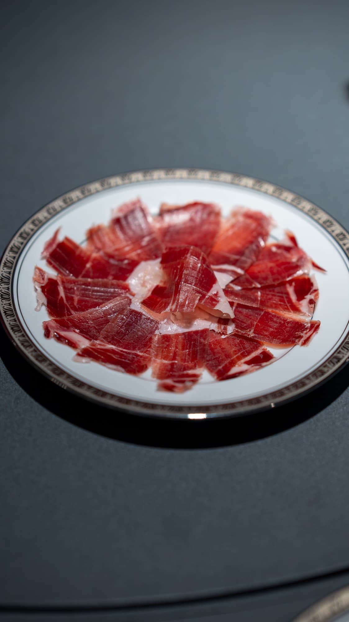 Fatias de jamón ibérico servidas em porcelana com fio dourado